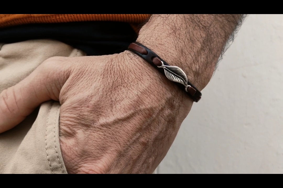 pulsera de cuero y hoja en baño de plata en muñeca de hombre